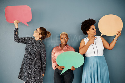 Buy stock photo Studio shot of a group of attractive young businesswomen holding speech bubbles while standing against a grey background