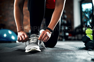 Buy stock photo Cropped shot of an unrecognizable young female athlete tying her laces while working out in the gym