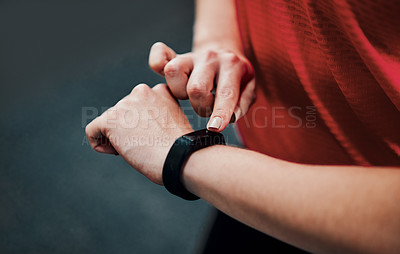 Buy stock photo Cropped shot of an unrecognizable young female athlete checking her smartwatch while working out in the gym