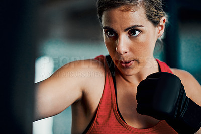 Buy stock photo Cropped shot of an attractive young female kickboxer working out in the gym