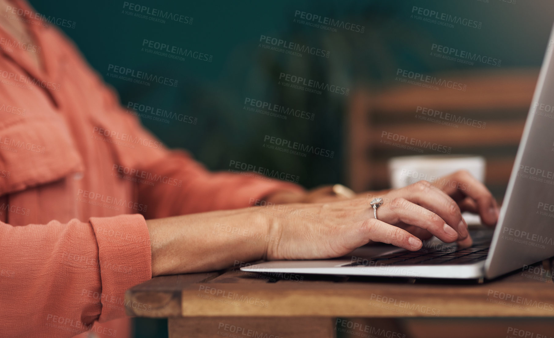 Buy stock photo Cropped shot of an unrecognisable woman typing on a laptop inside of a coffee shop during the day