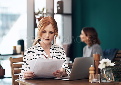 Buy stock photo Cropped shot of an attractive middle aged woman doing paperwork while being seated inside of a coffee shop during the day