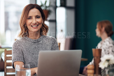 Buy stock photo Portrait of an attractive middle aged woman working on her laptop while being seated inside of a coffee shop during the day