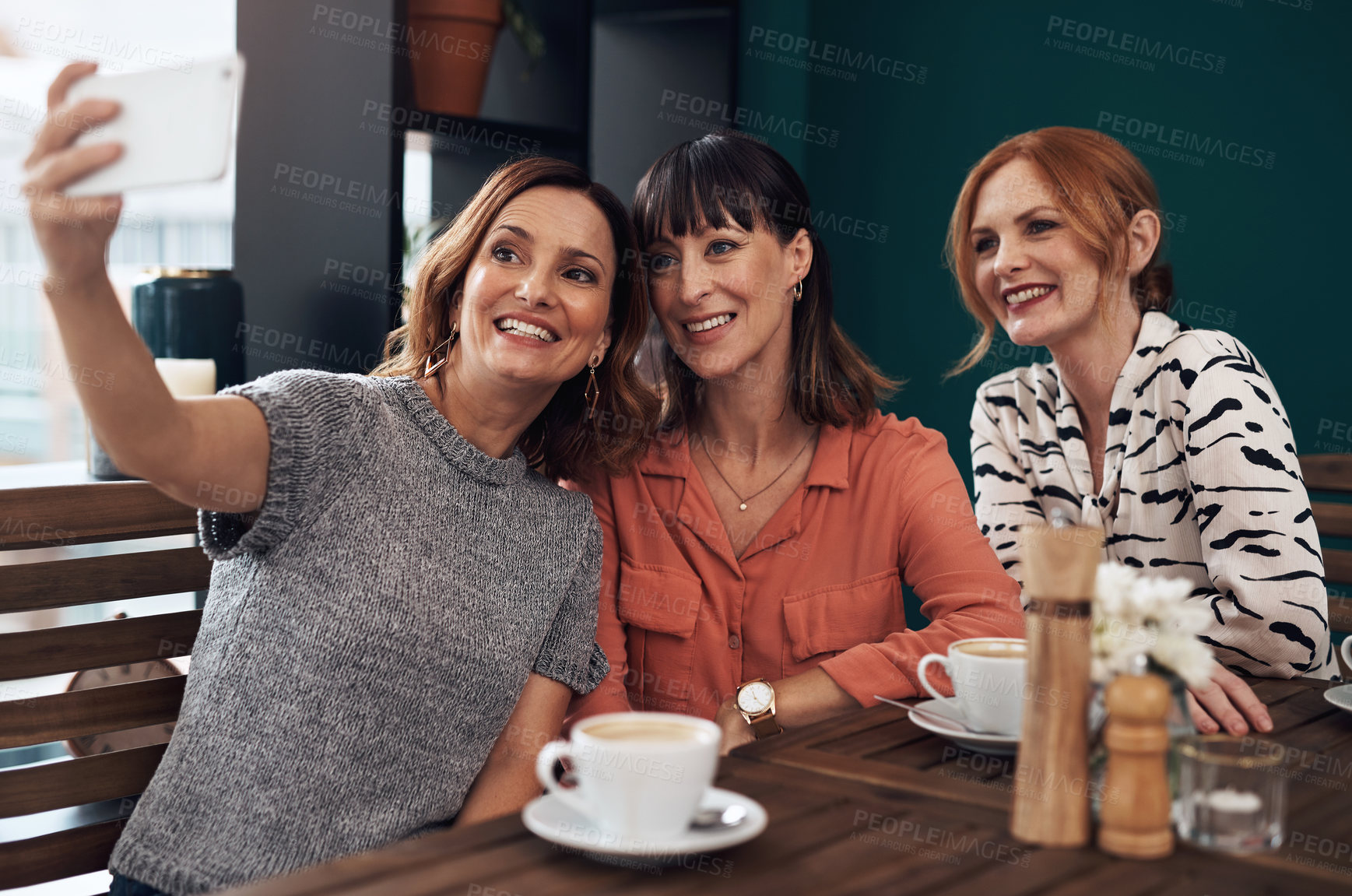 Buy stock photo Cropped shot of a group of attractive middle aged women taking a self portrait together while being seated inside of a coffee shop during the day