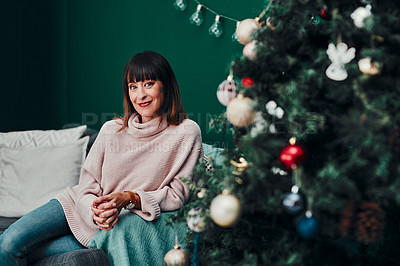 Buy stock photo Portrait of an attractive middle aged woman sitting together on a sofa next to a Christmas tree at home