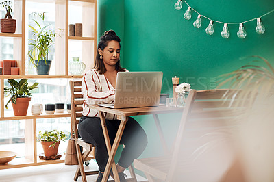 Buy stock photo Shot of a young woman using a laptop at a cafe