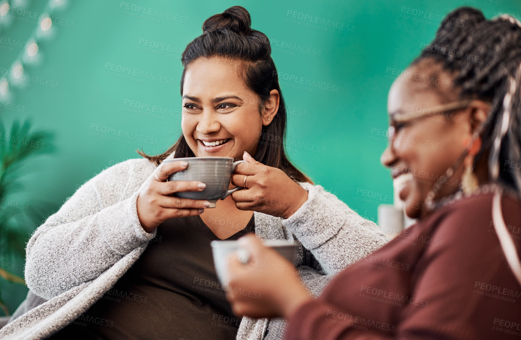 Buy stock photo Shot of two young women having coffee and chatting on the sofa at home