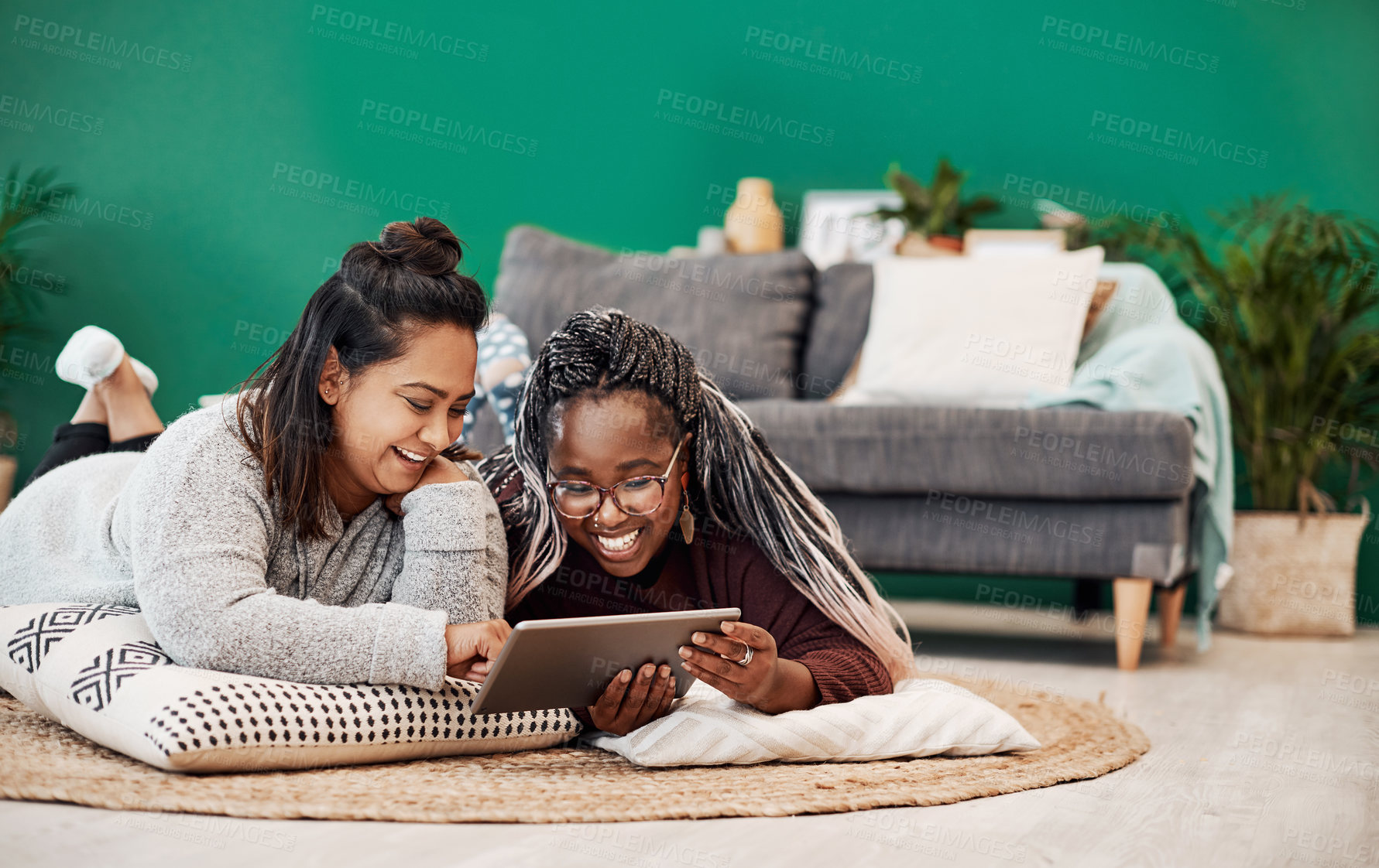 Buy stock photo Shot of two young women using a digital tablet together on the floor at home