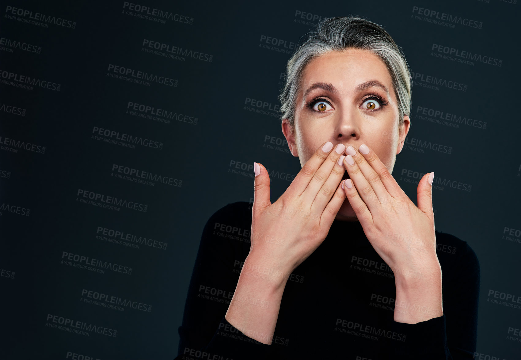 Buy stock photo Studio portrait of a beautiful mature woman looking surprised against a dark background