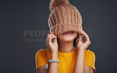 Buy stock photo Cropped shot of an unrecognizable teenage girl wearing a beanie and feeling playful against a dark studio background