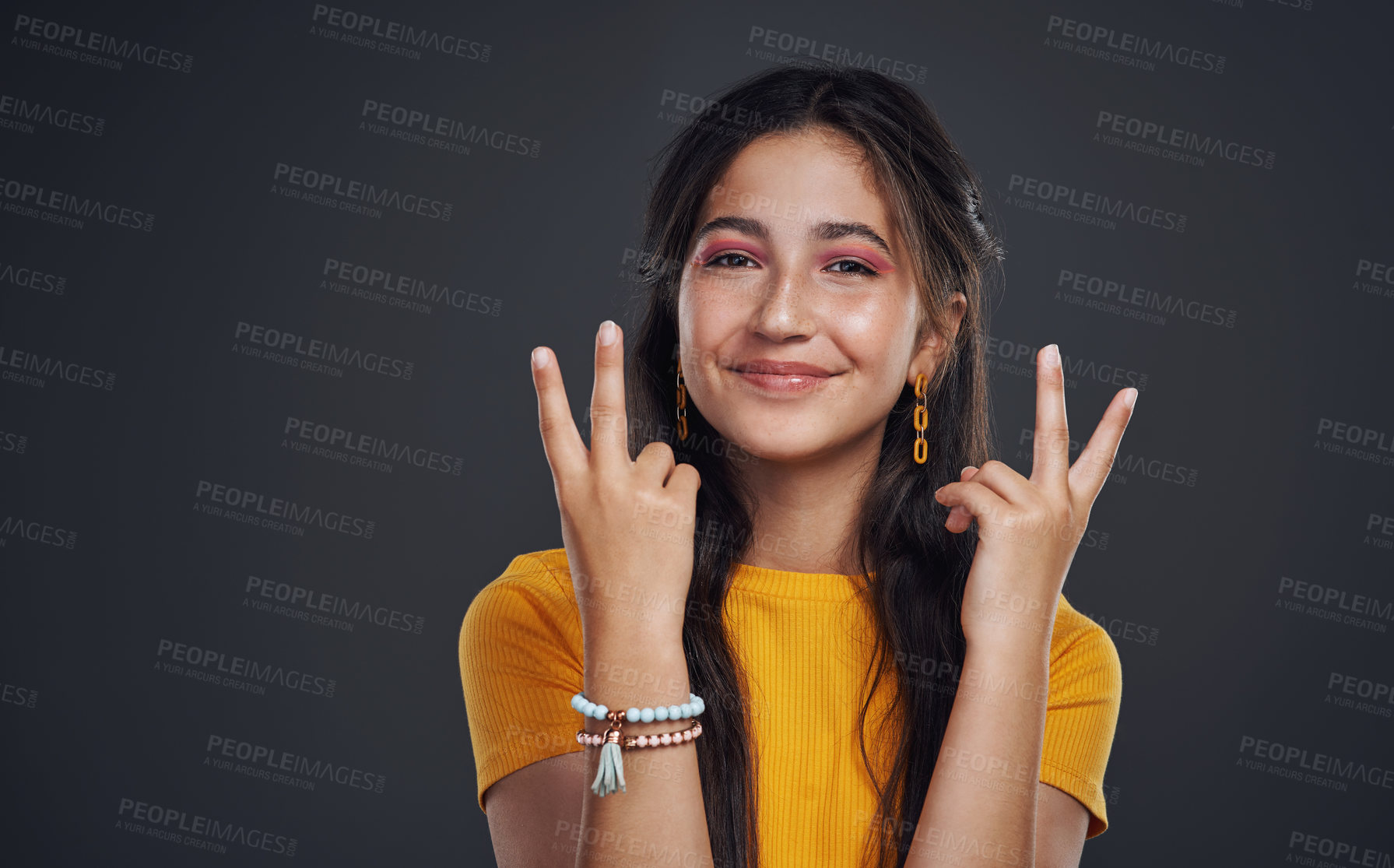 Buy stock photo Cropped portrait of an attractive teenage girl standing alone and feeling playful against a dark background in the studio