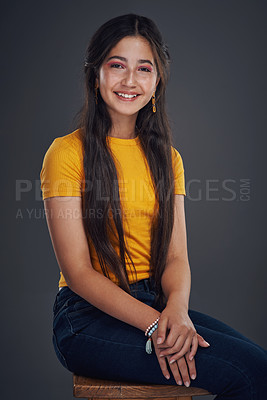 Buy stock photo Cropped portrait of an attractive teenage girl sitting alone against a dark background in the studio