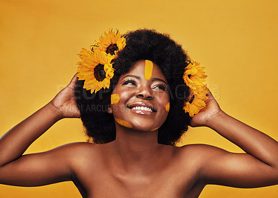 Buy stock photo Studio shot of a beautiful young woman smiling while posing with sunflowers in her hair against a mustard background