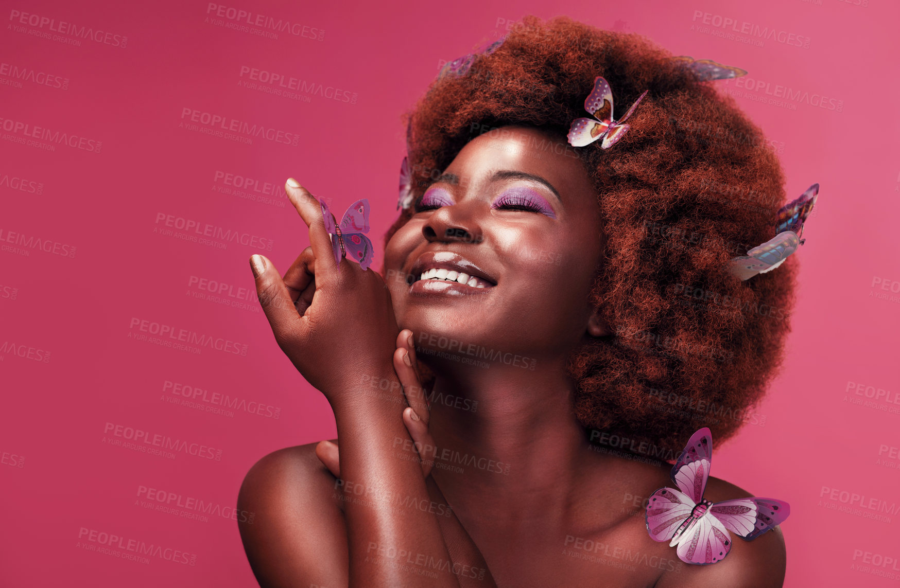 Buy stock photo Studio shot of a beautiful young woman smiling while posing with butterflies in her hair against a purple background