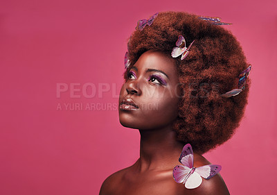 Buy stock photo Creative, cosmetic and woman with butterflies in her hair and a makeup, natural and elegant face. Art, fantasy and young African female model posing with beautiful insects by a pink studio background