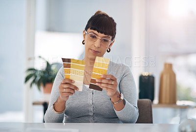 Buy stock photo Cropped shot of an attractive young businesswoman sitting alone in her office and looking at a colour swatch