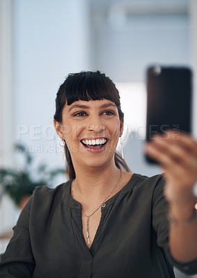 Buy stock photo Cropped shot of an attractive young businesswoman sitting alone in her office and using her cellphone to take a selfie