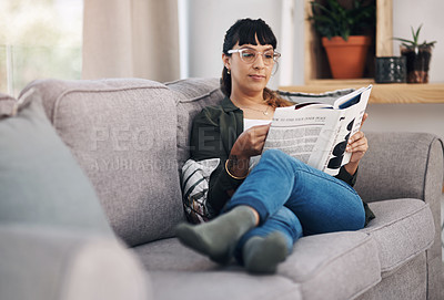 Buy stock photo Full length shot of an attractive young woman sitting alone in her living room and reading a book