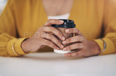 Buy stock photo Cropped shot of an unrecognizable businesswoman sitting alone in her office and holding a cup of coffee