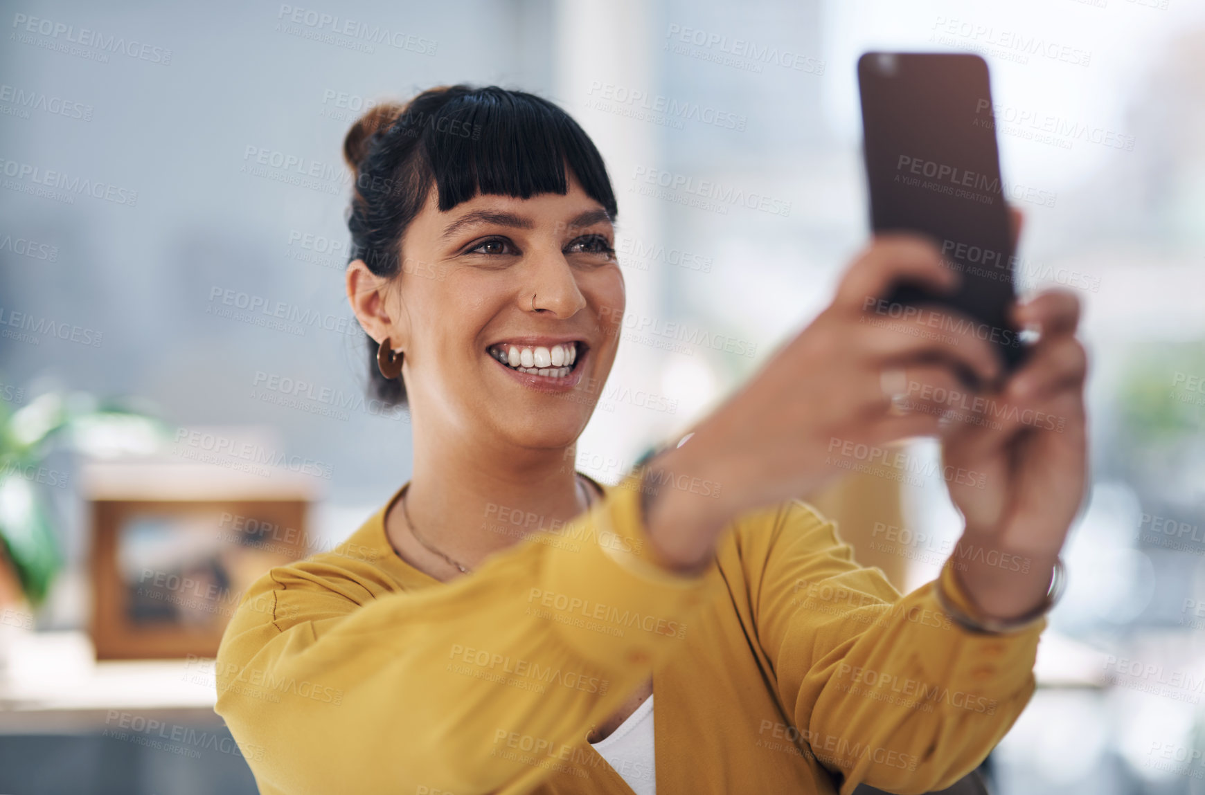 Buy stock photo Cropped shot of an attractive young businesswoman sitting alone in her office and using her cellphone to take a selfie