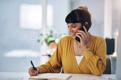 Buy stock photo Cropped shot of attractive young businesswoman sitting alone in her office talking on her cellphone while writing notes
