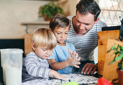 Buy stock photo Shot of a young man baking with his two adorable sons at home