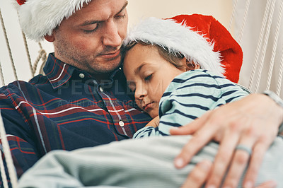 Buy stock photo Shot of an adorable little boy having a nap with his father in a hammock at Christmas