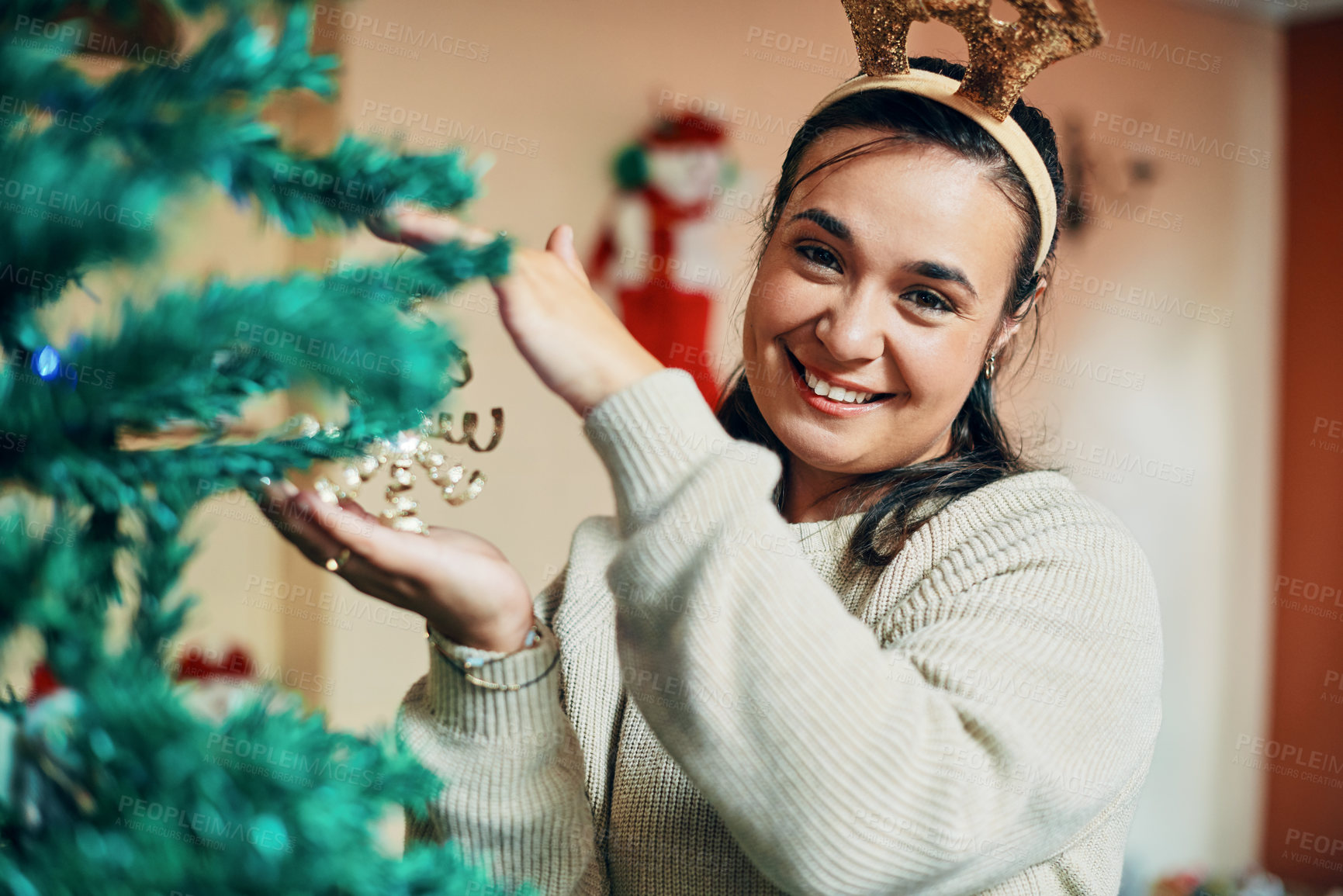 Buy stock photo Portrait of a happy young woman decorating her Christmas tree at home