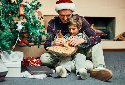 Buy stock photo Shot of an adorable little boy unwrapping Christmas presents with his father at home