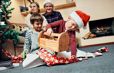 Buy stock photo Shot of two adorable little boys unwrapping Christmas presents with their parents at home