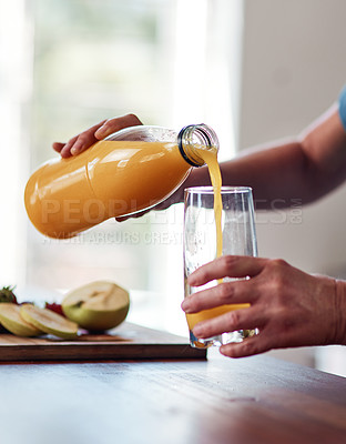 Buy stock photo Cropped shot of an unrecognizable senior woman pouring herself a glass of orange juice while preparing breakfast in the kitchen