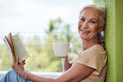 Buy stock photo Cropped portrait of an attractive senior woman enjoying a cup of coffee while reading a book outside on her balcony at home