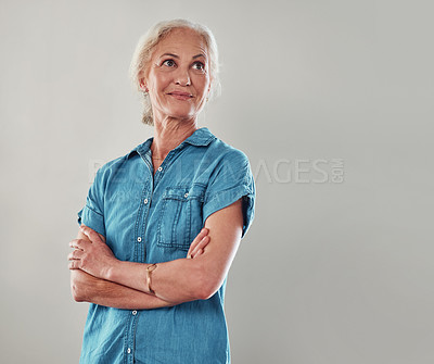 Buy stock photo Cropped shot of an attractive senior woman looking contemplative while standing with her arms folded against a grey background