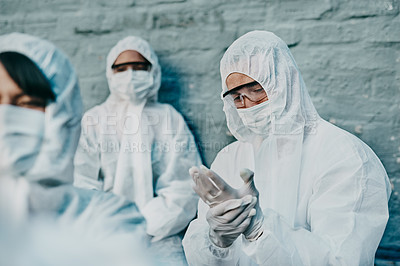 Buy stock photo Covid, pandemic and team healthcare workers wearing protective ppe to prevent virus spread at a quarantine site. Concerned first responder wearing a hazmat suit and checking his safety glove
