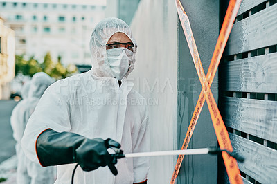 Buy stock photo Healthcare worker in covid pandemic, sanitizing and cleaning area with disinfectant, barrier or caution tape and a face mask. Emergency medical person in hazmat suit working in coronavirus crisis