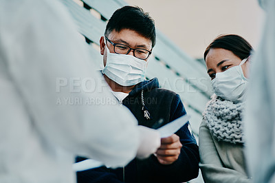 Buy stock photo Shot of a young man talking to a healthcare worker in a hazmat suit during an outbreak