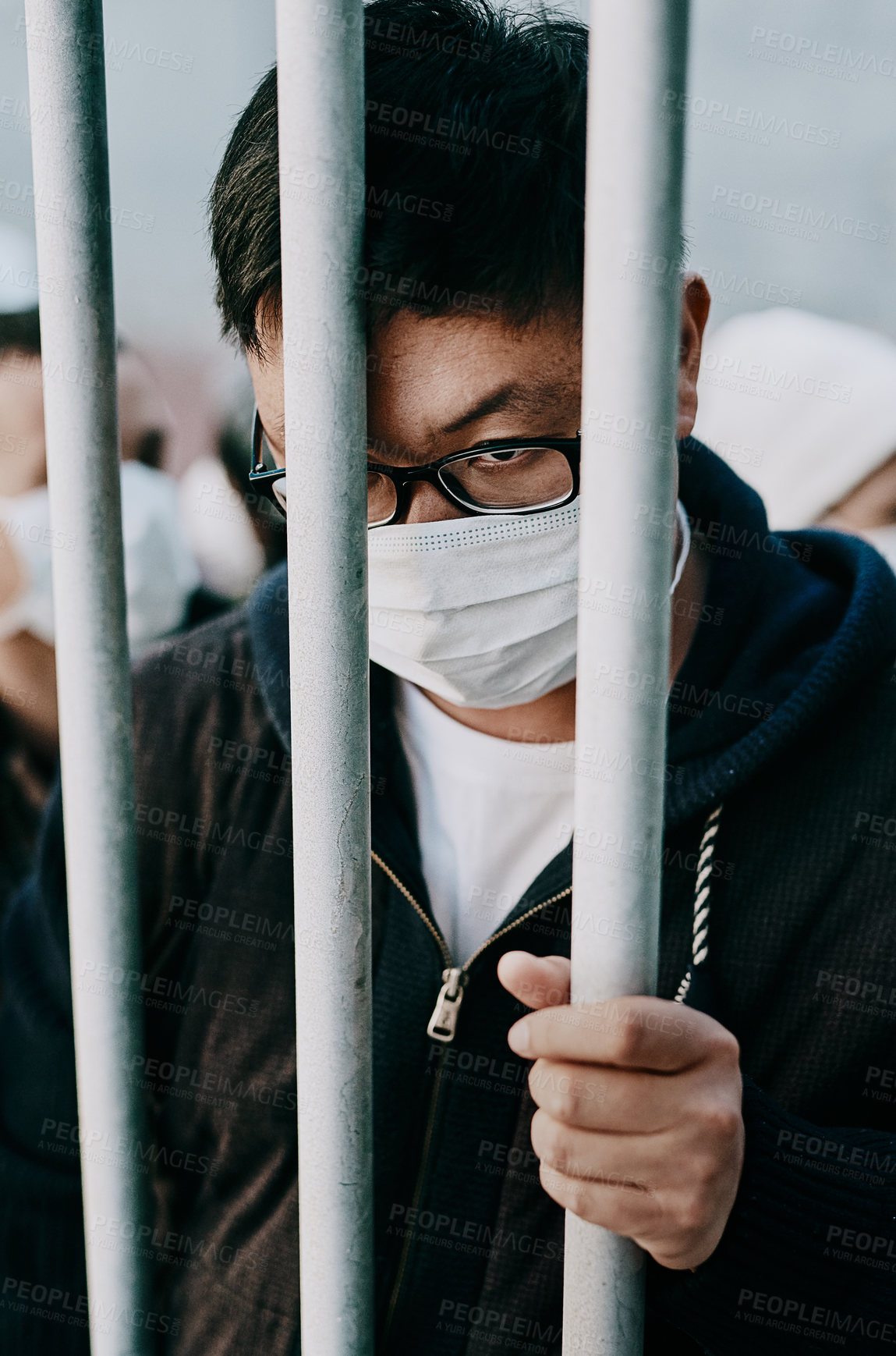 Buy stock photo Lockdown, isolation and covid travel ban with a man in a mask behind bars during an international pandemic. Corona virus restrictions, feeling like a prisoner or captive during a global shutdown