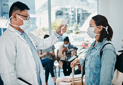 Buy stock photo Covid traveling with a doctor taking temperature of a woman wearing a mask in an airport for safety in a pandemic. Healthcare professional with an infrared thermometer following travel protocol