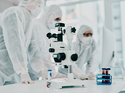 Buy stock photo Sterile, white and modern room with a closeup of a microscope and medical scientists or group conducting research for corona. Clinical and bright laboratory with doctors working on a blood sample. 
