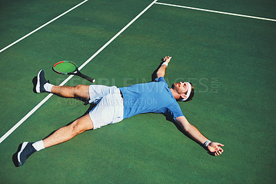 Buy stock photo Full length shot of a handsome young male tennis player lying down on a tennis court outdoors