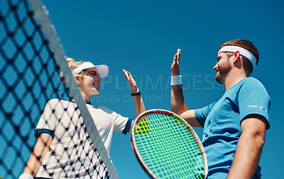Buy stock photo Low angle shot of two young tennis players giving each other a high five outdoors on the court