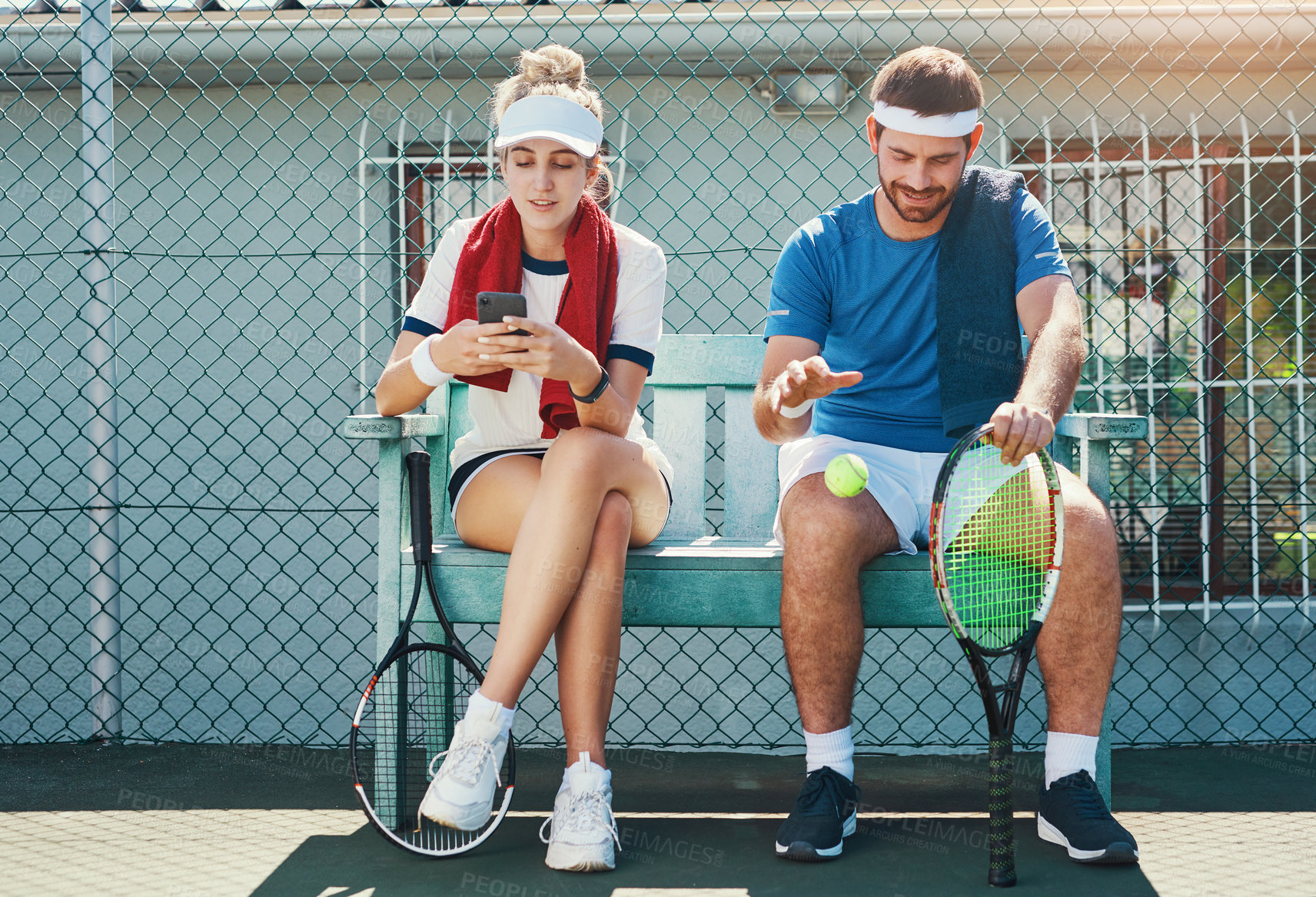 Buy stock photo Full length shot of two young tennis players sitting down and having a conversation together outdoors on the court