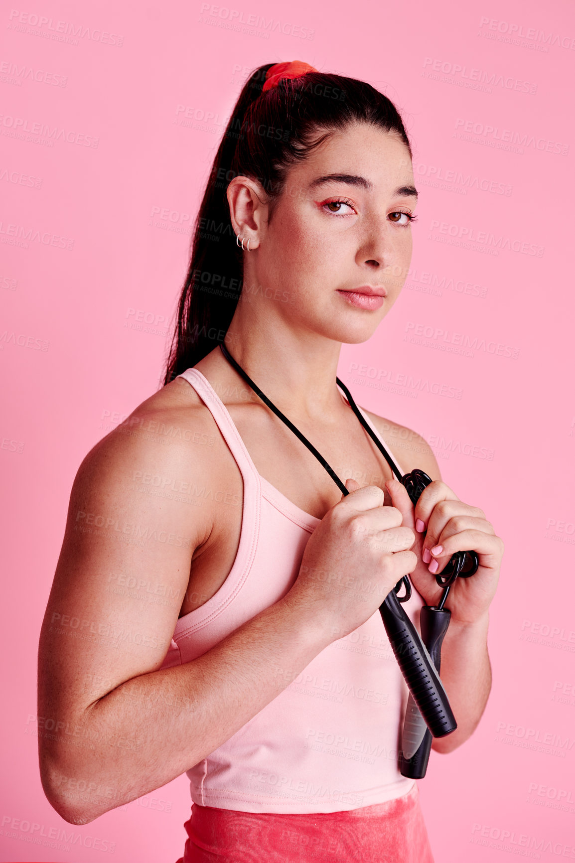 Buy stock photo Studio portrait of a sporty young woman holding a skipping rope around her neck against a pink background