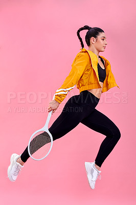 Buy stock photo Studio shot of a sporty young woman jumping with a tennis racket against a pink background