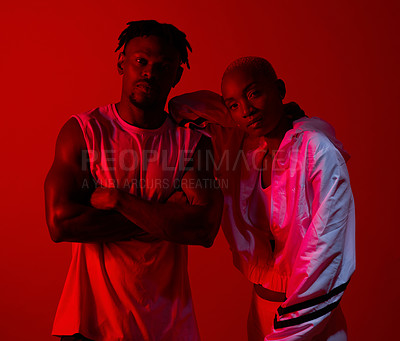 Buy stock photo Red filtered shot of a sporty young man and woman posing together in the studio