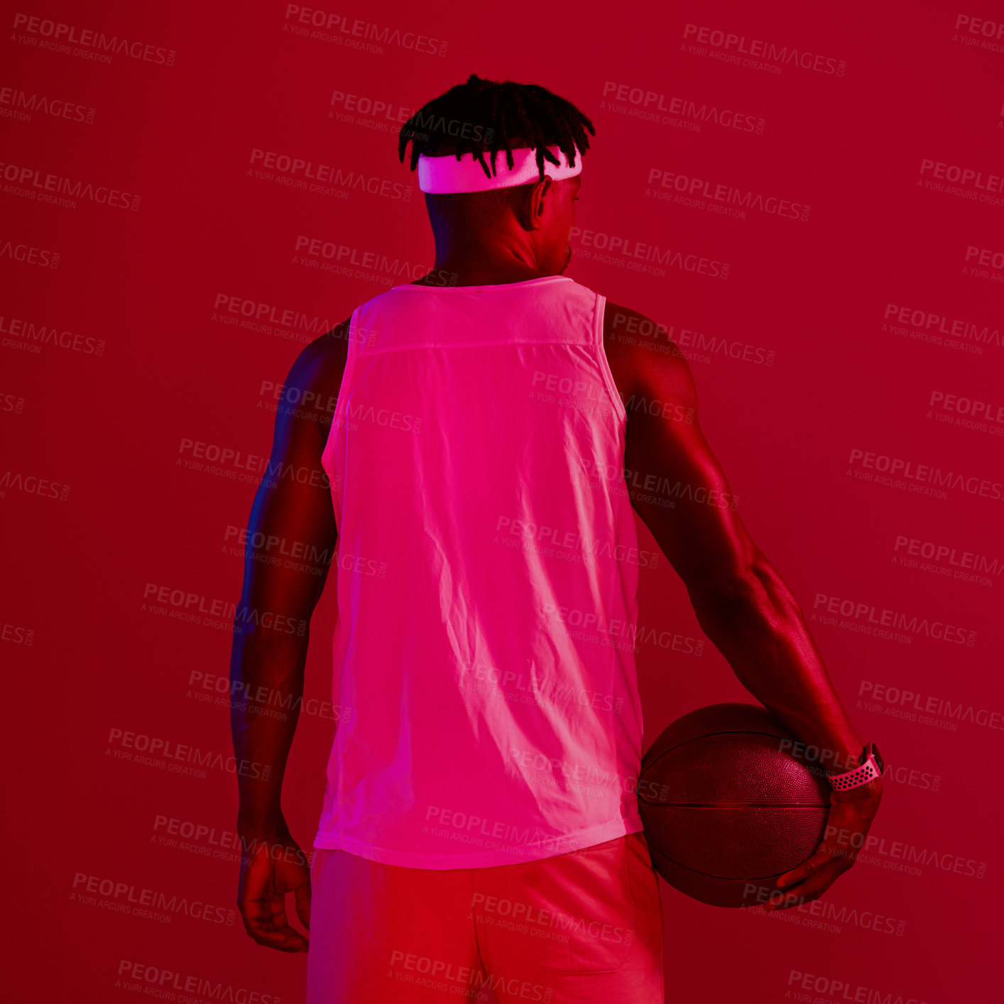 Buy stock photo Red filtered shot of a young sportsman posing with a basketball in the studio