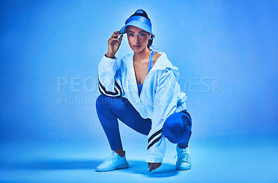 Buy stock photo Full length portrait of an attractive young female athlete posing on her haunches against a blue background