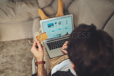 Buy stock photo Shot of an unrecognizable man using his laptop and credit card while relaxing on a couch at home