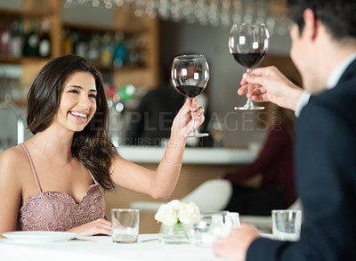 Buy stock photo Shot of a happy young couple toasting with wine on a romantic date at a restaurant