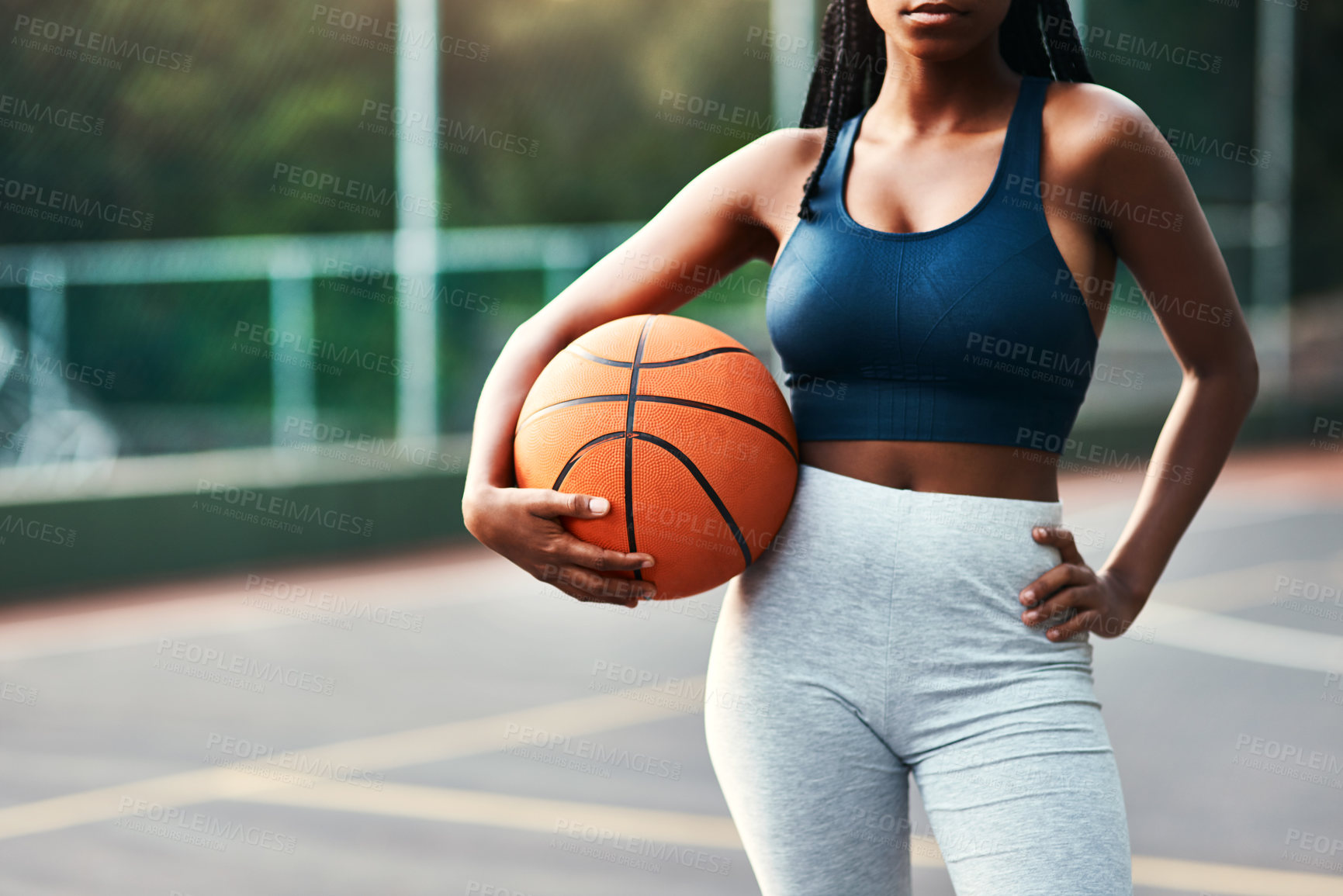 Buy stock photo Cropped shot of an unrecognizable sportswoman standing on the court alone and holding a basketball during the day